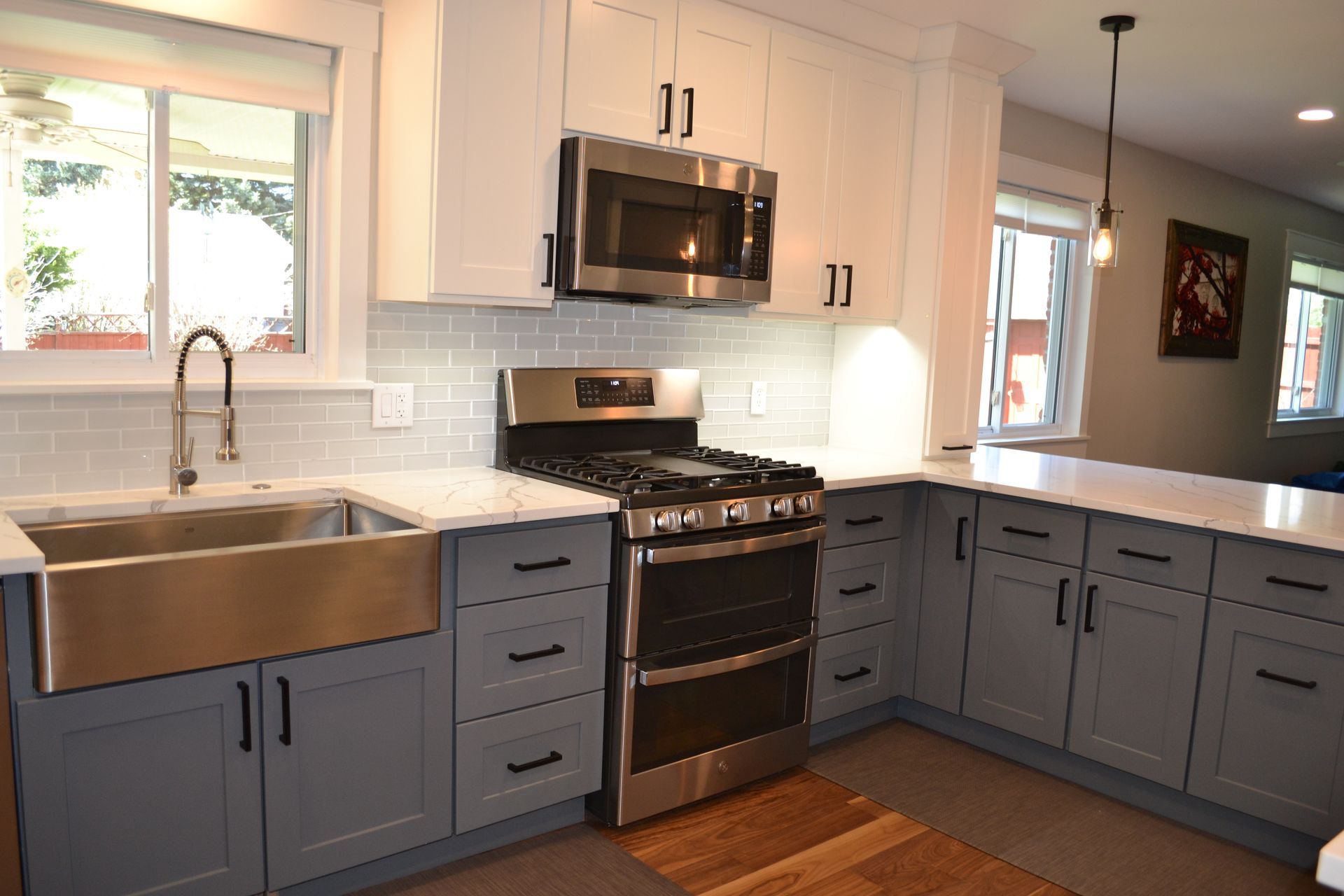 Modern kitchen with gray and white cabinets, stainless steel appliances, and a farmhouse sink.
