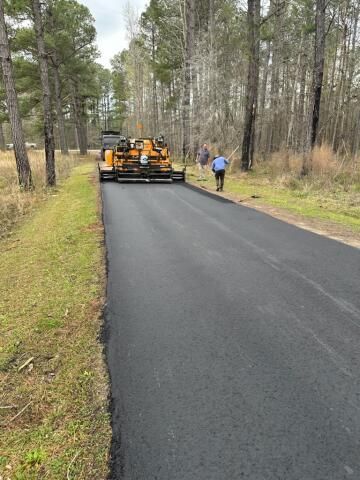 A man is using a yellow machine on a driveway