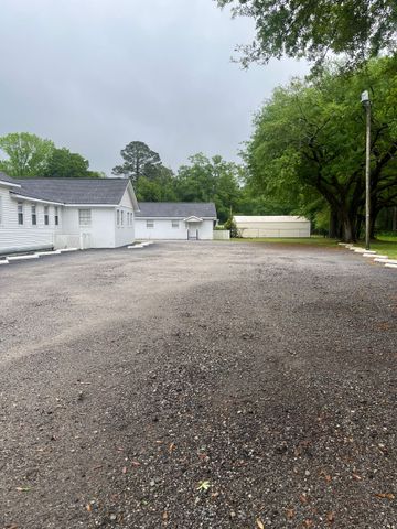 A man is spreading asphalt on a driveway in front of a garage door.