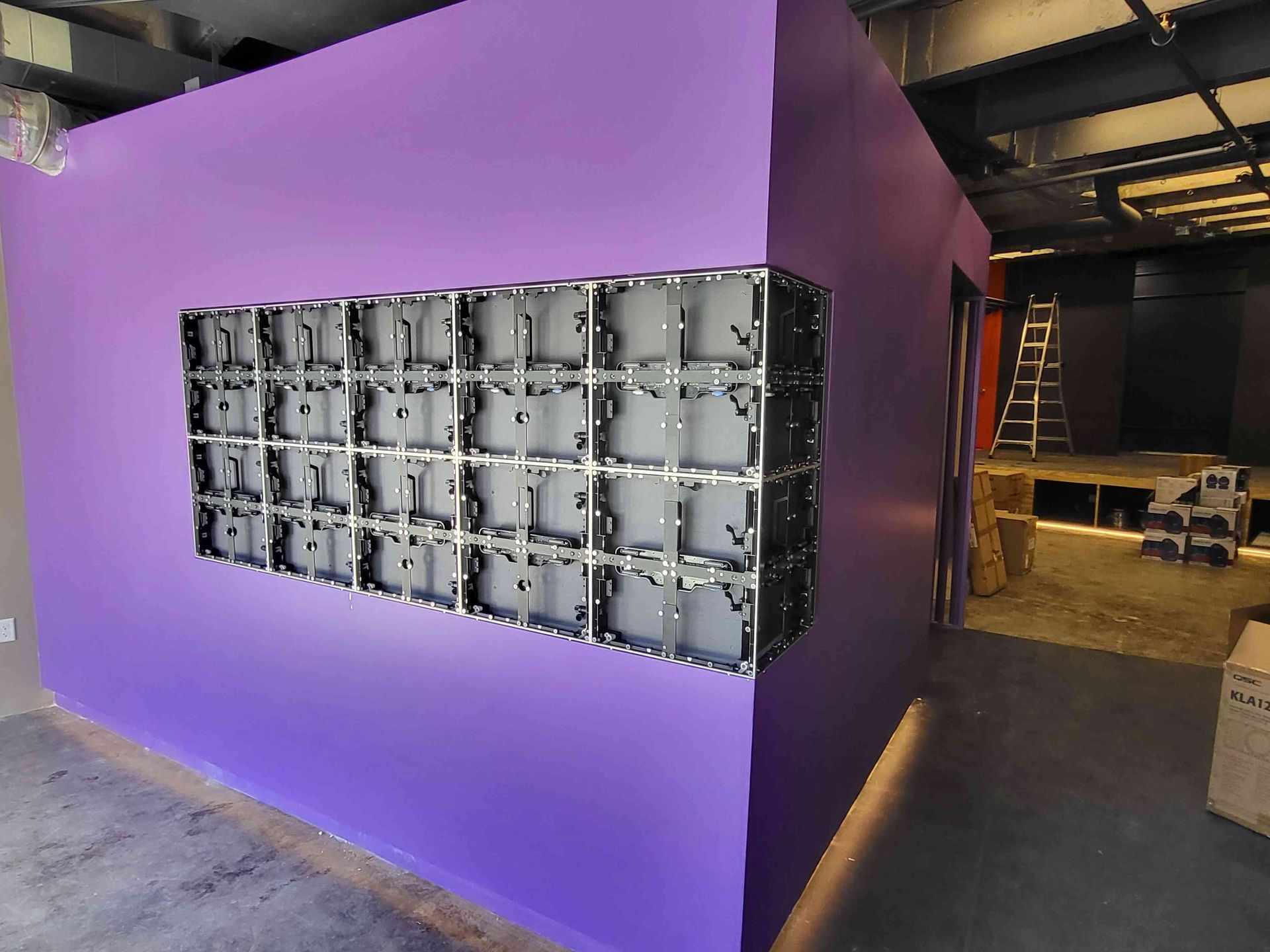 Wall with partially installed LED display; purple wall, open doorway.