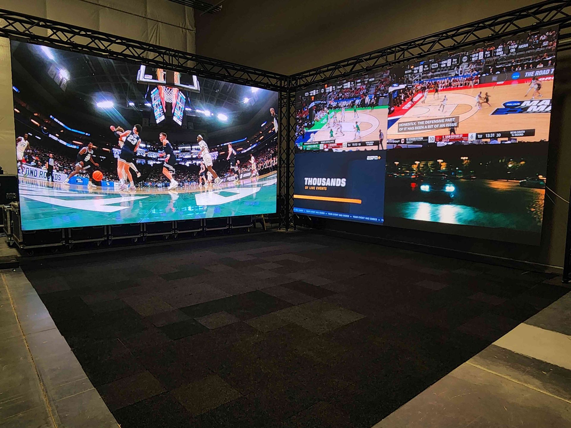 Two large LED screens at right angles displaying basketball game footage in a studio space.