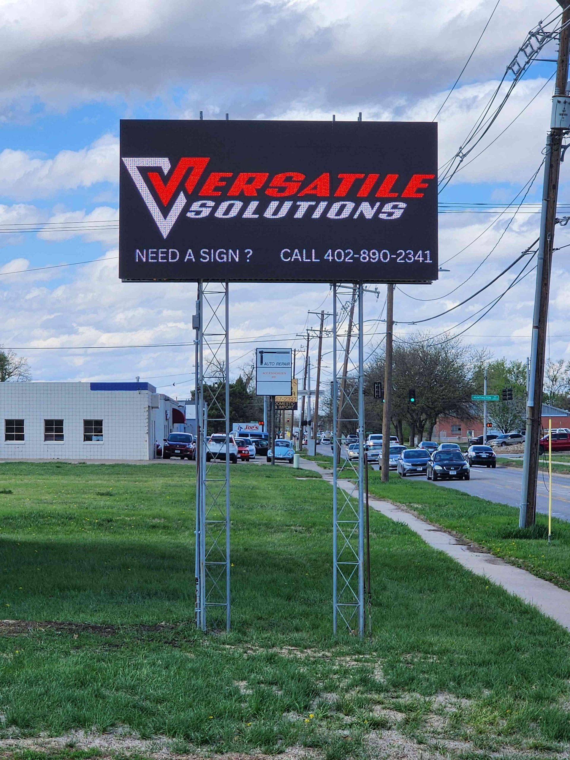 Sign for Versatile Solutions, red logo on black background. Text says 