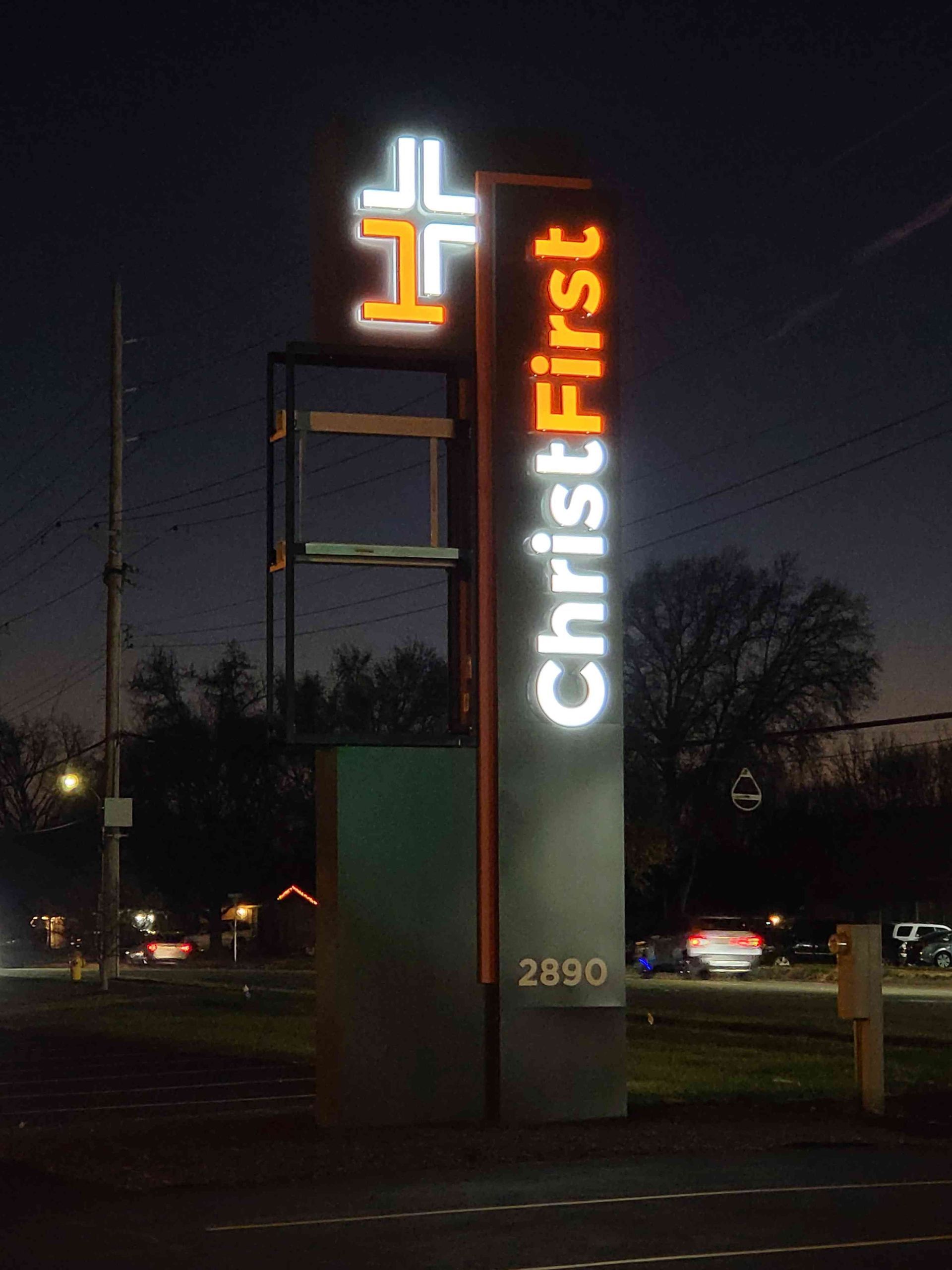 ChristFirst Church sign at night with illuminated cross and text, 