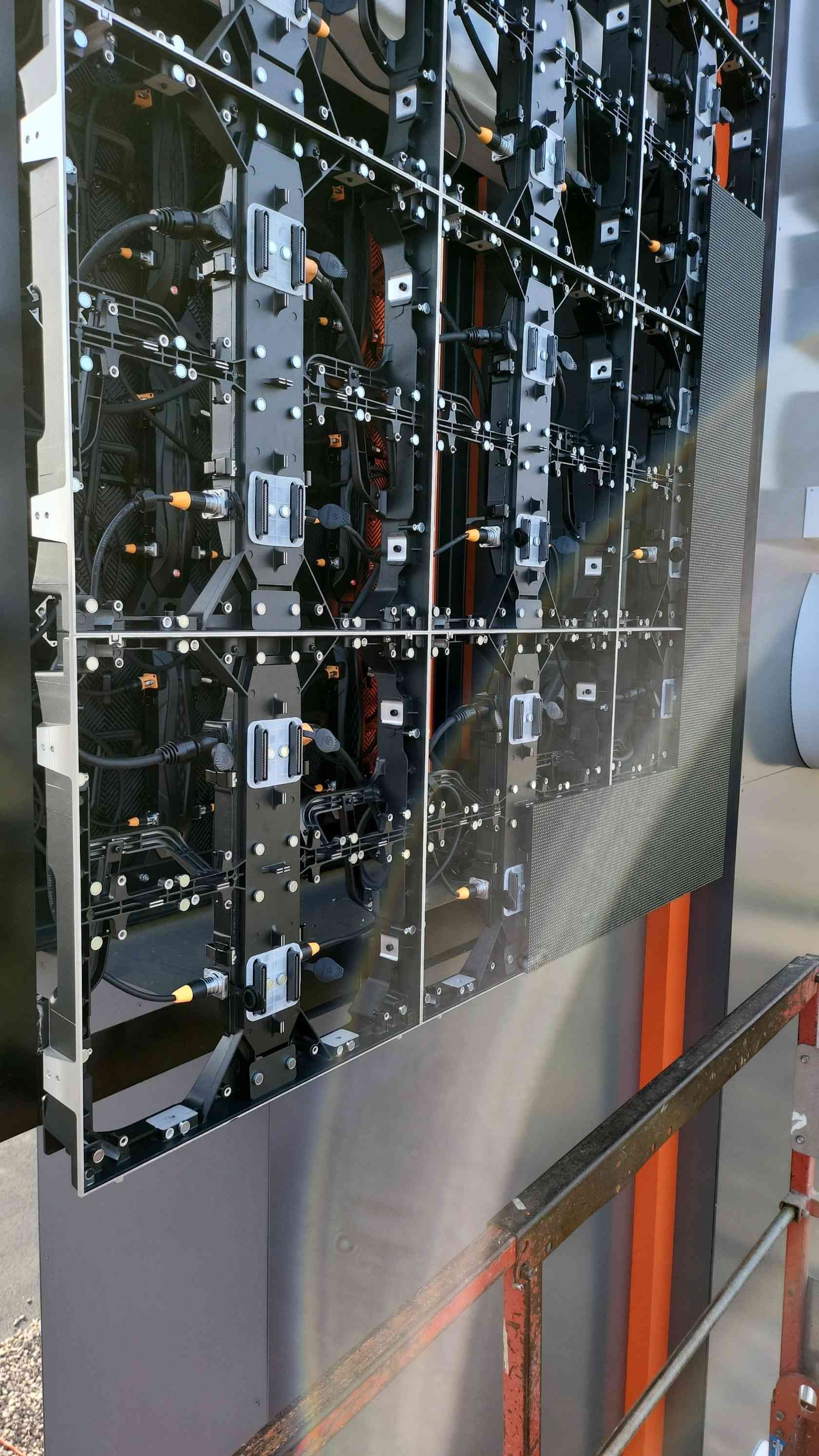 Back of an LED screen panel, showing internal wiring and components, mounted on a metal structure.