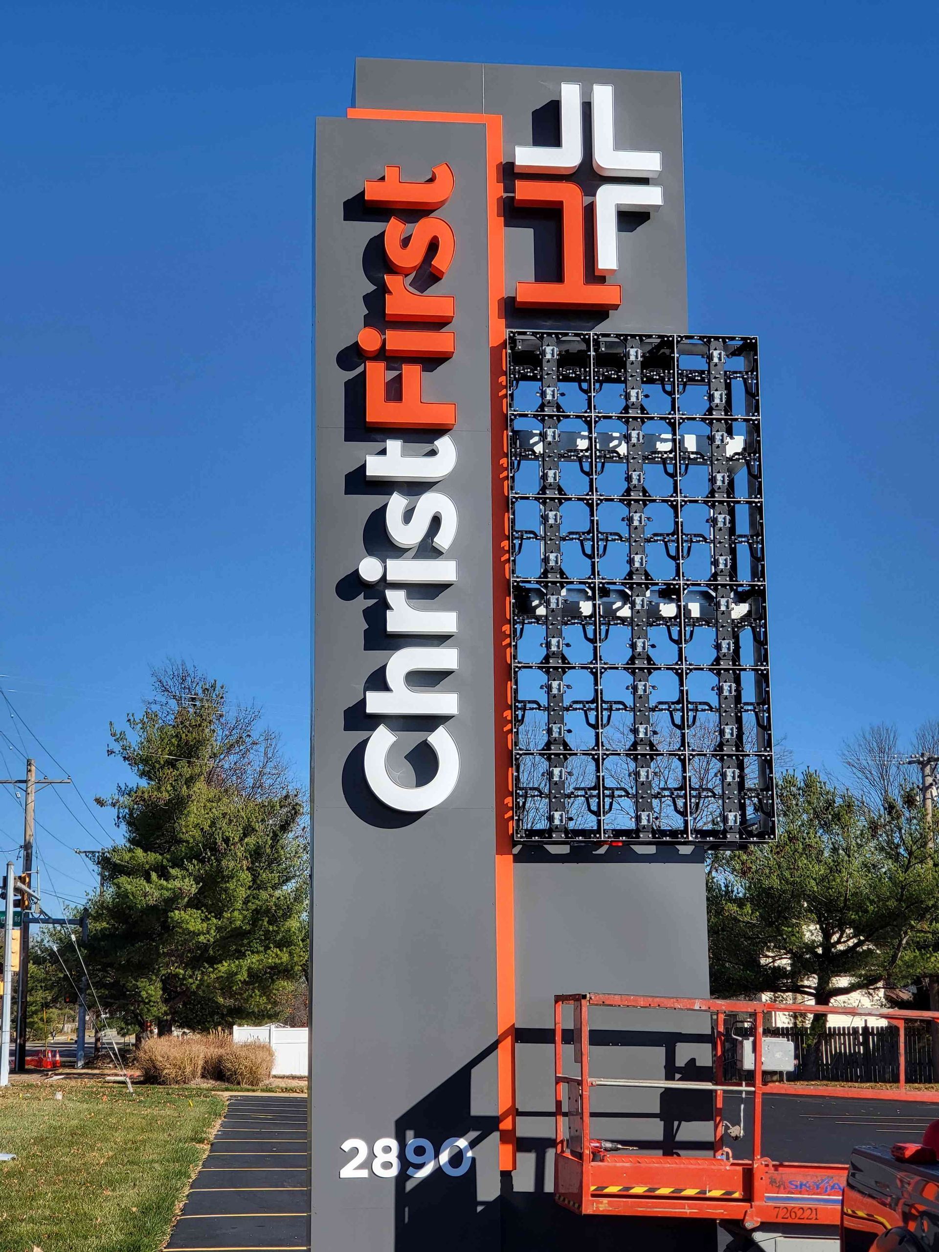 Sign for Christ First Church, gray and orange, with white text and cross, incomplete LED panel.