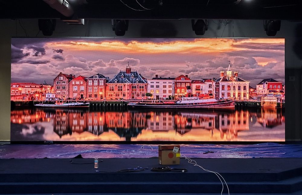 Large LED screen displaying a colorful waterfront city at sunset, with water reflections.