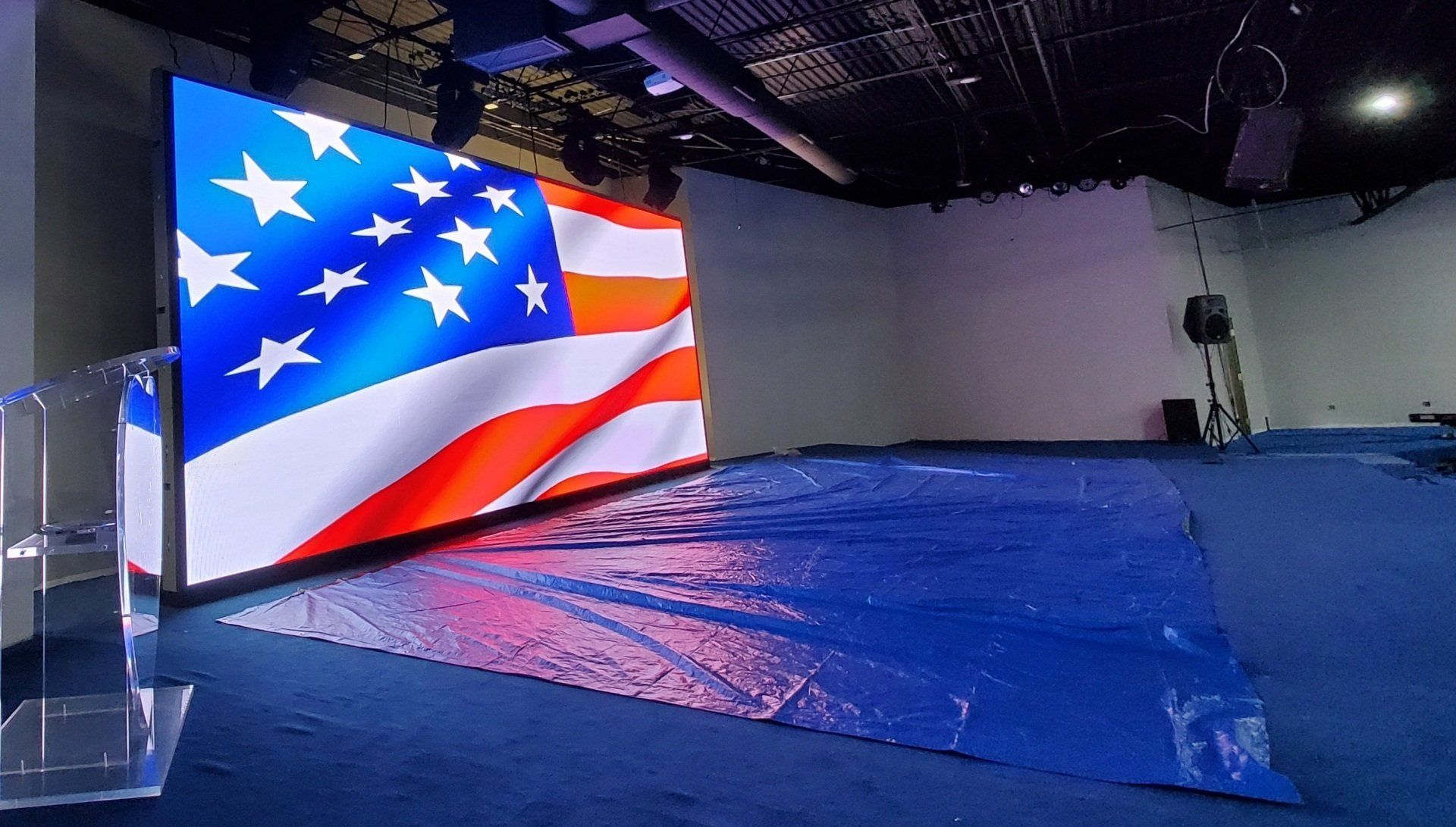 American flag display on a screen, blue carpet, empty room.