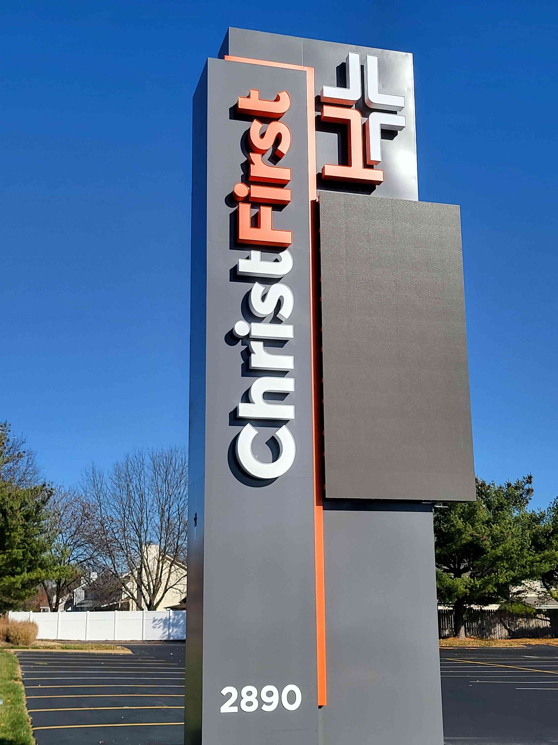 Sign for Christ First church; gray and orange tower with white text and cross icon; 2890 address.