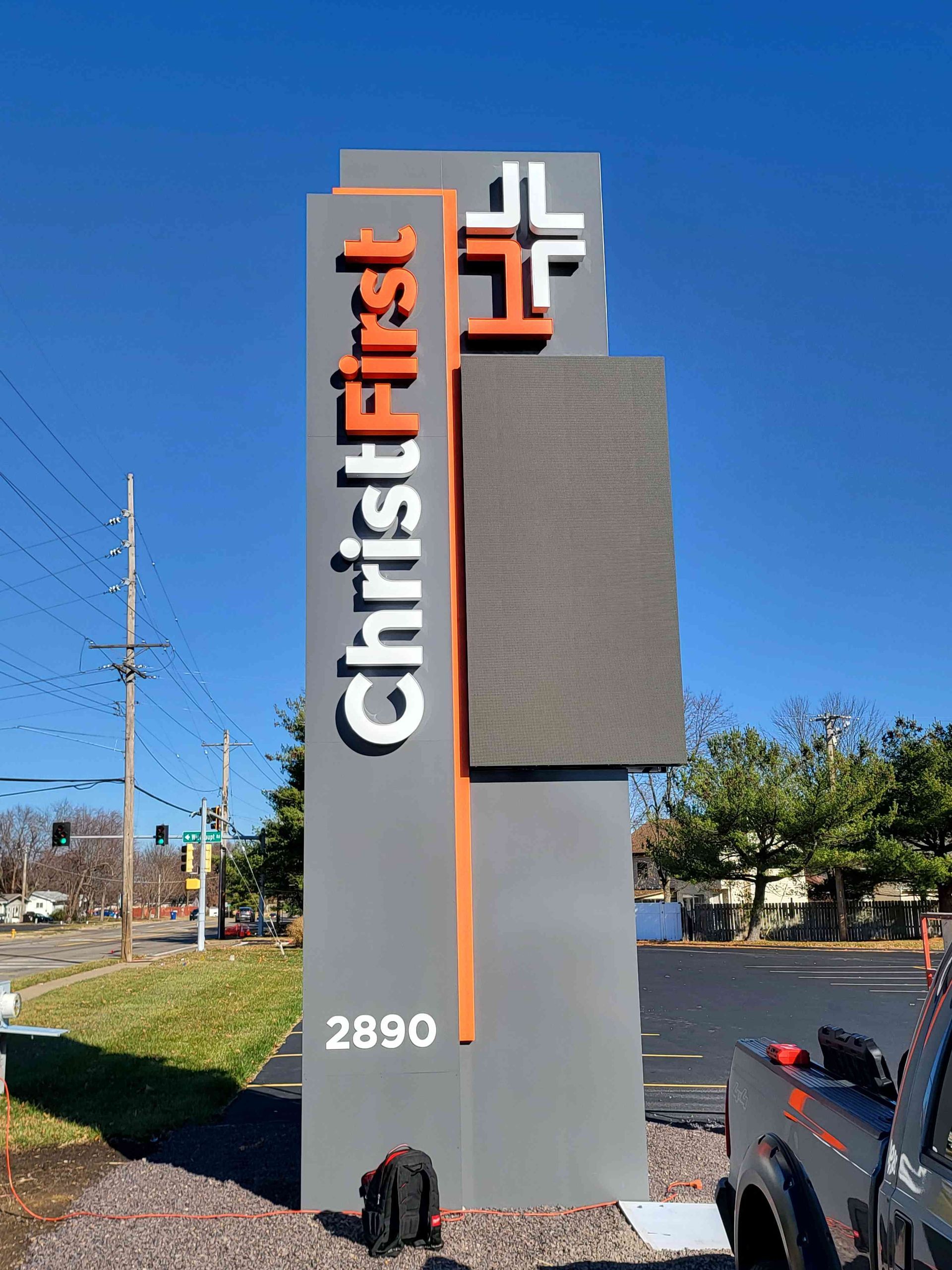 Sign for Christ First church, gray with orange accents and LED panel. 2890 address visible.