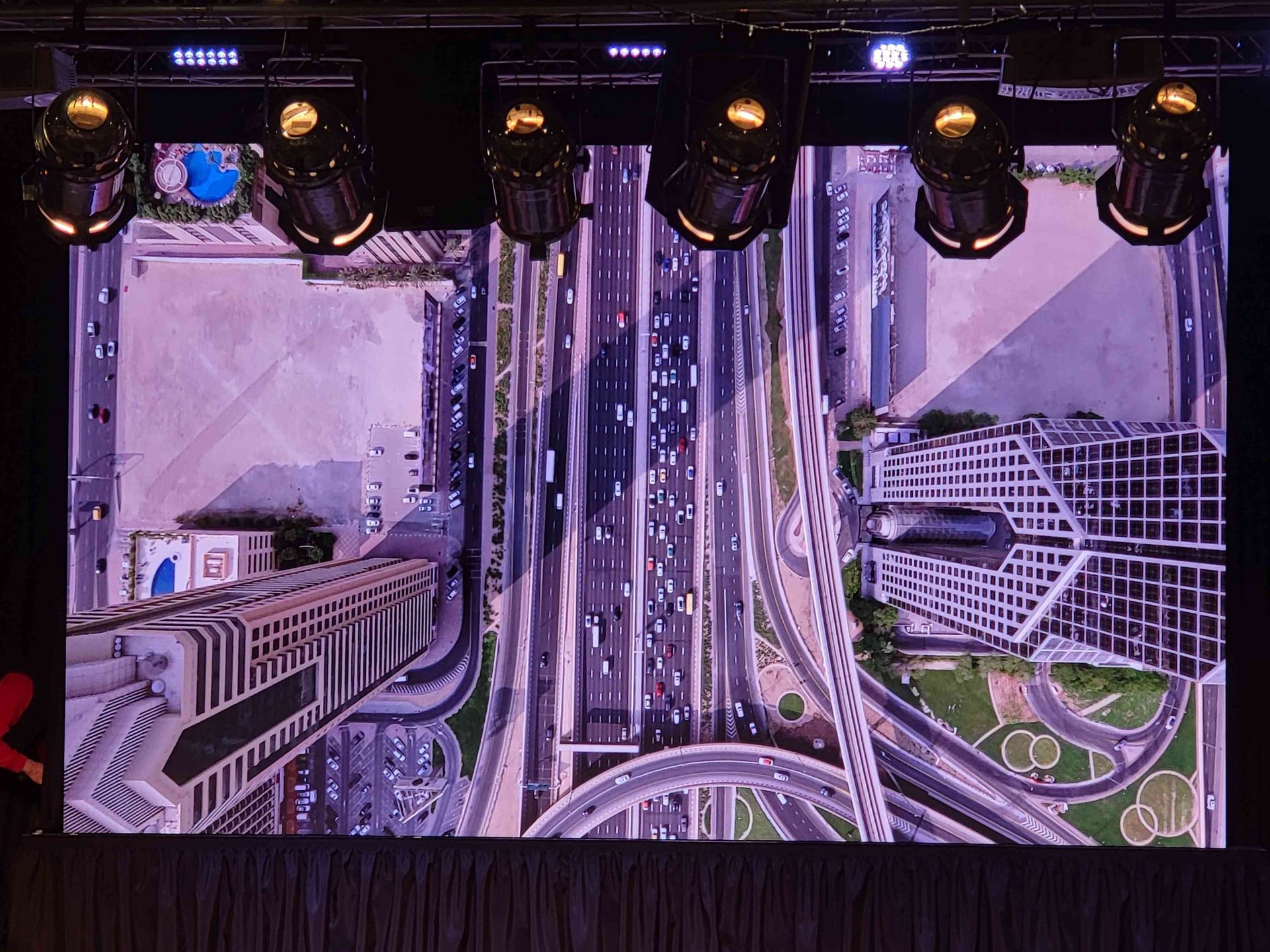 Overhead view of city highways and buildings, with cars and elevated roadways.