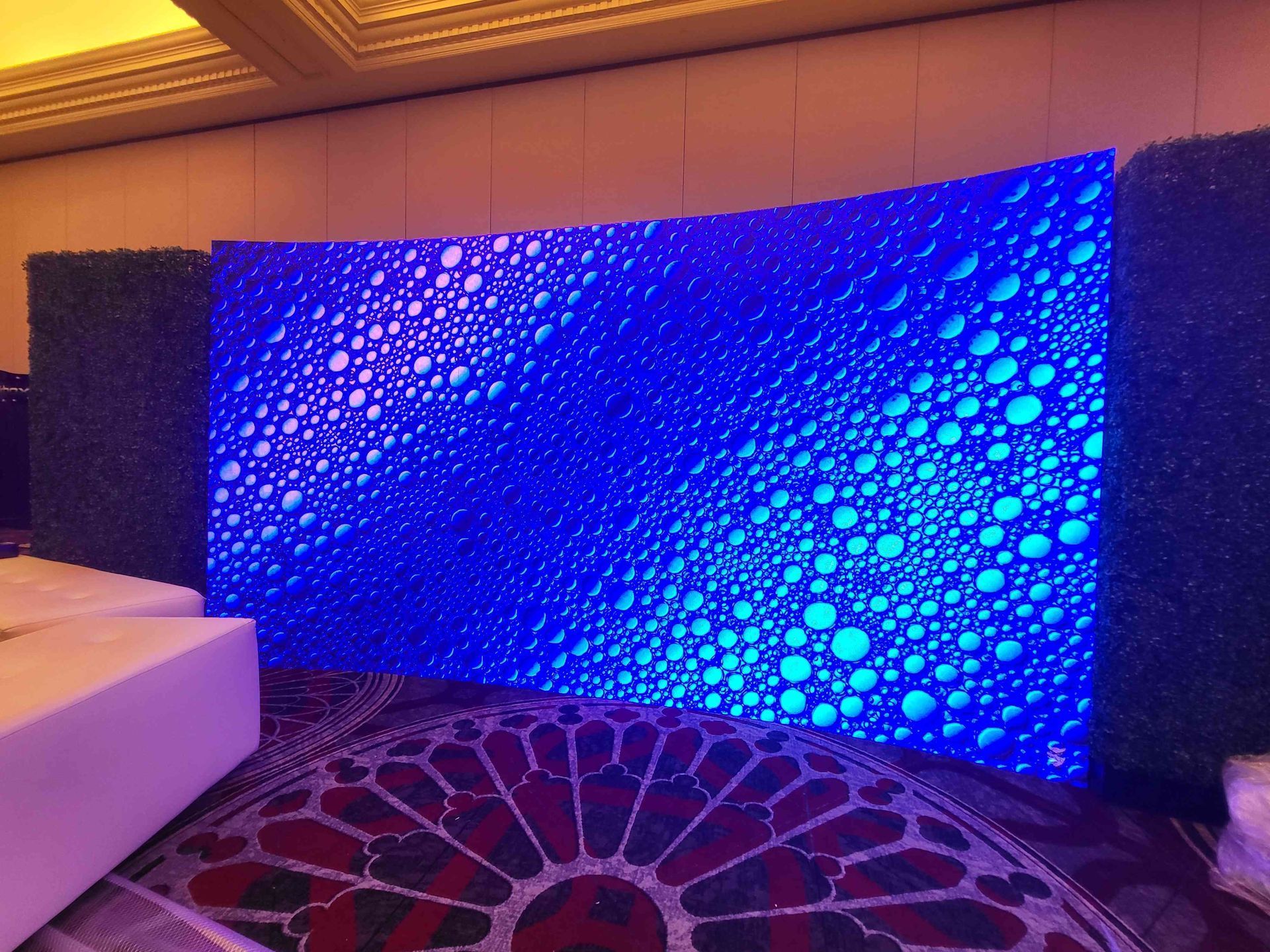 A large, curved blue LED wall with a bubble-like pattern is set up at an event.