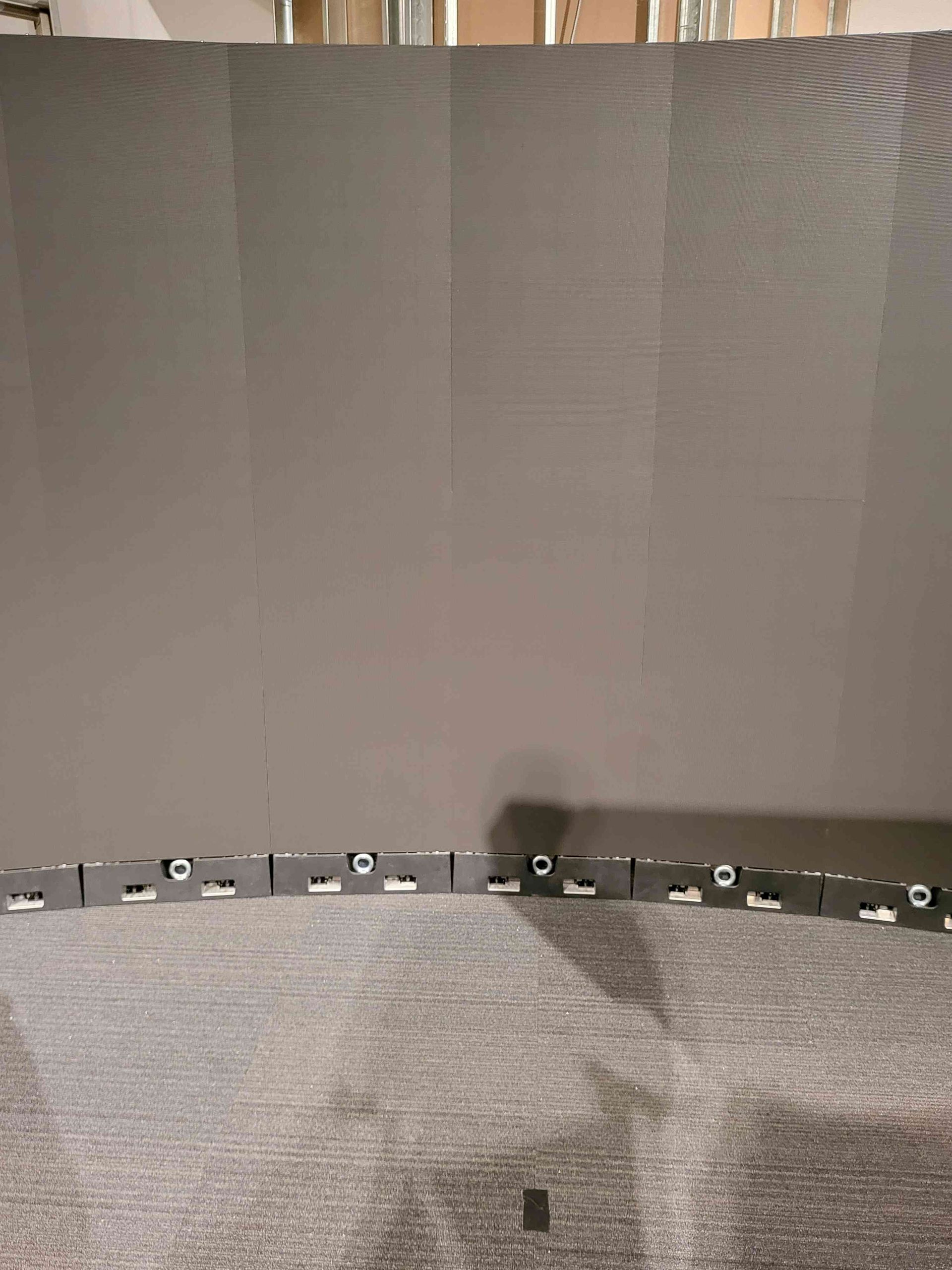 Gray wall with a row of small, dark boxes along the bottom, on a gray carpet.