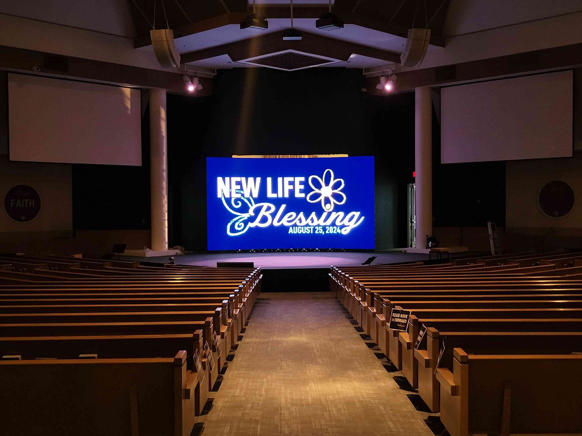 Church auditorium with rows of pews facing a stage displaying 