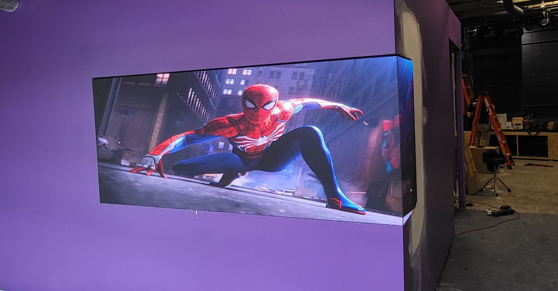 Spider-Man on an LED screen, mounted on a purple wall.