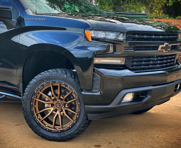 Black Chevrolet Silverado truck with bronze wheels.