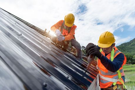 Two construction workers are working on a roof.