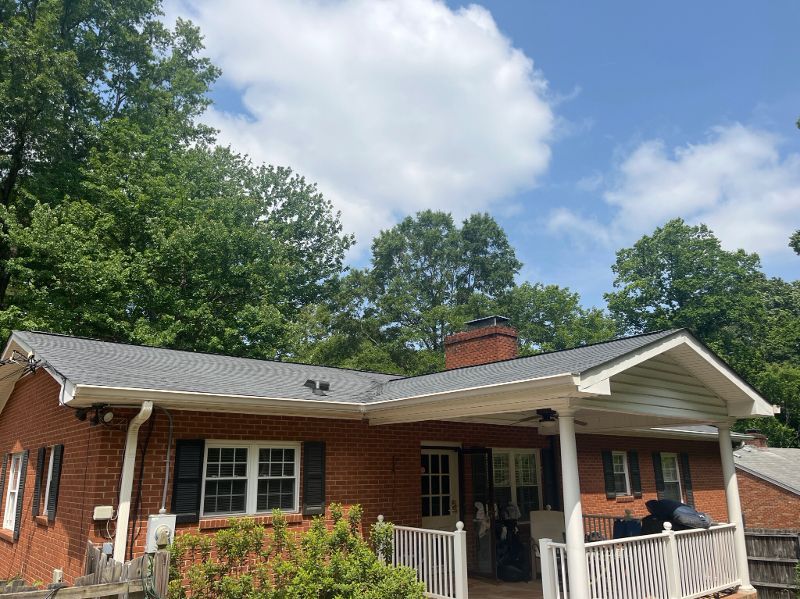 A brick house with a gray roof and a white porch.
