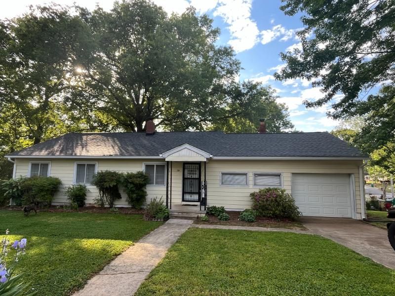 A white house with a black roof and a white garage door