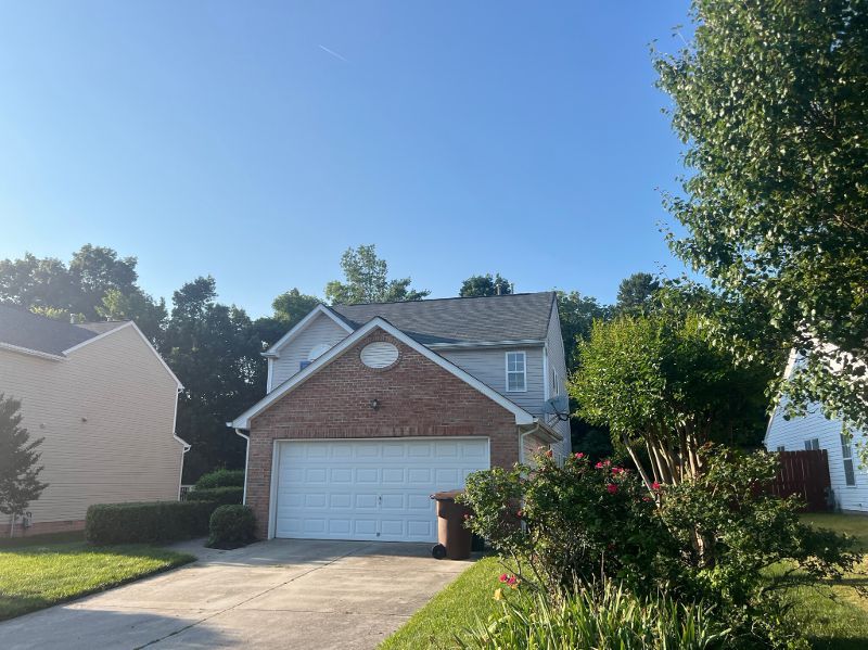A brick house with a white garage door and a blue sky in the background.