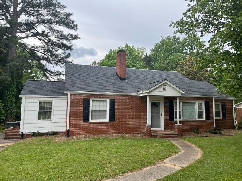 A brick house with a black roof and black shutters