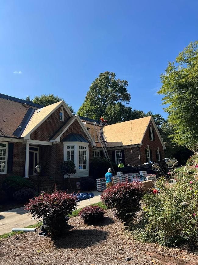 A man is standing on a ladder on the roof of a house.