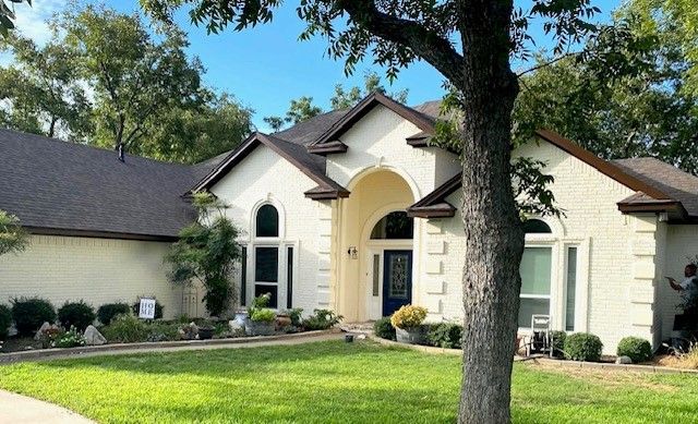 A white house with a tree in front of it.
