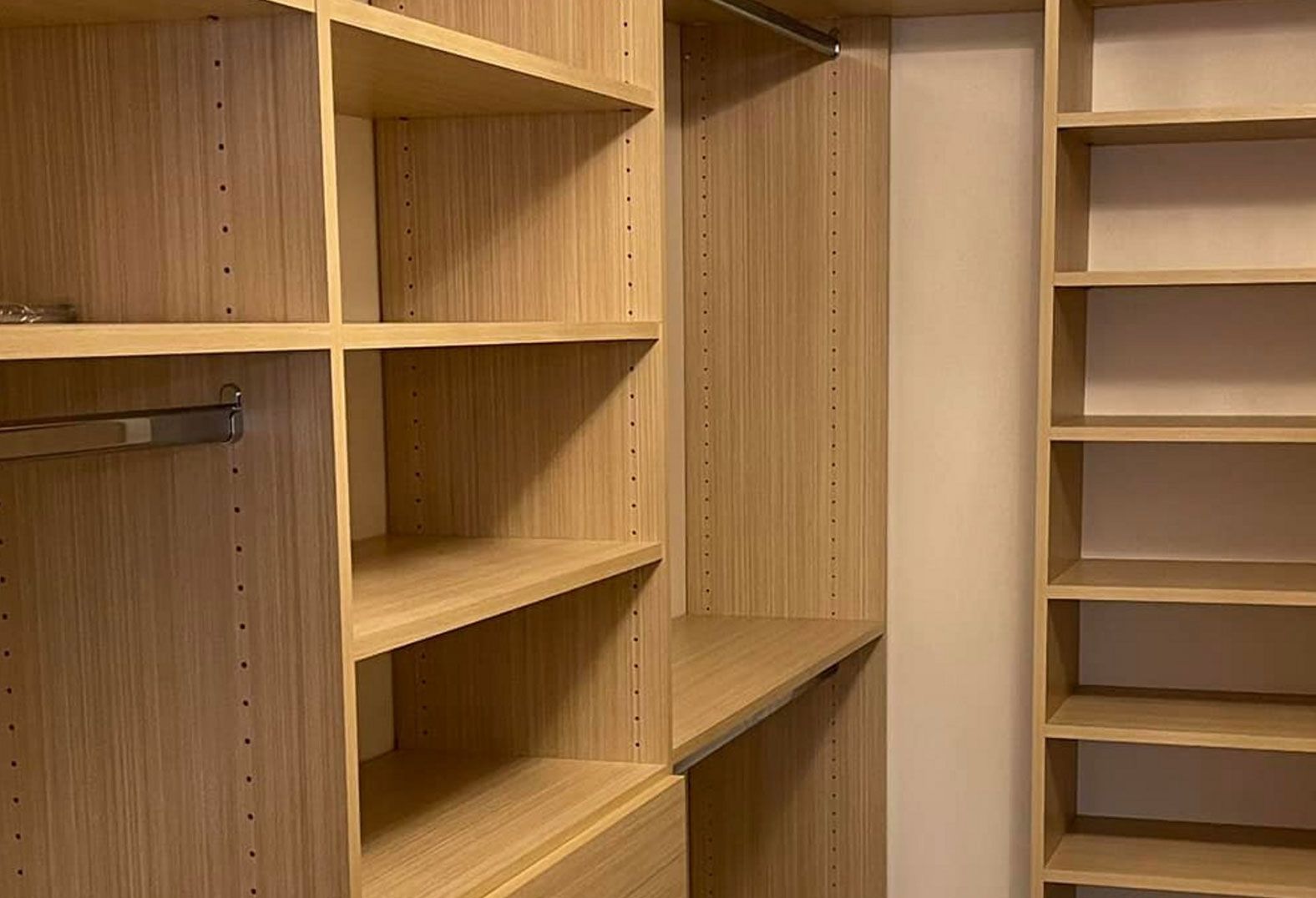 Built-in closet with light wood shelves and vertical supports, empty and ready for use.