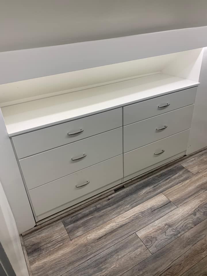 White six-drawer dresser built into a wall niche, silver handles.