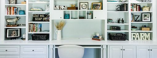 White built-in desk and bookshelves filled with decor items, books, and baskets.