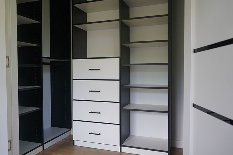 Closet with white and black shelves and drawers.