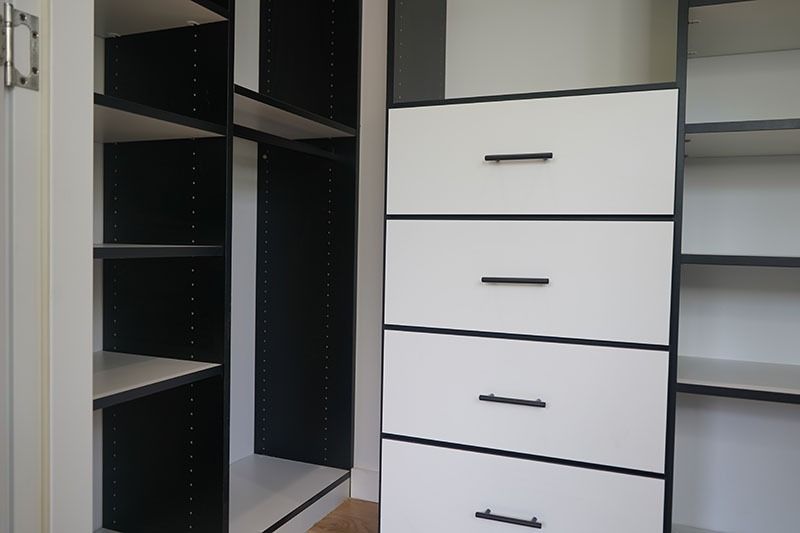 White and black closet interior with shelves and drawers.