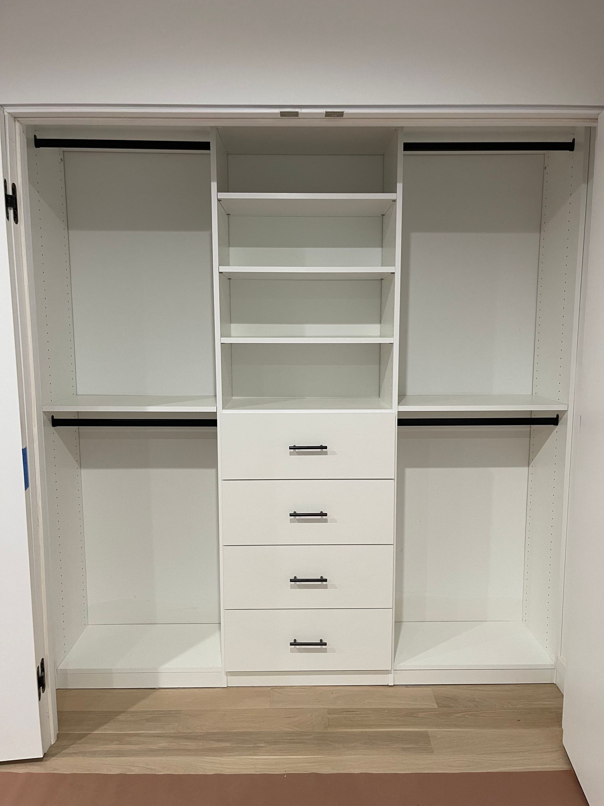 White closet with shelves, drawers, and hanging rods. Interior view.