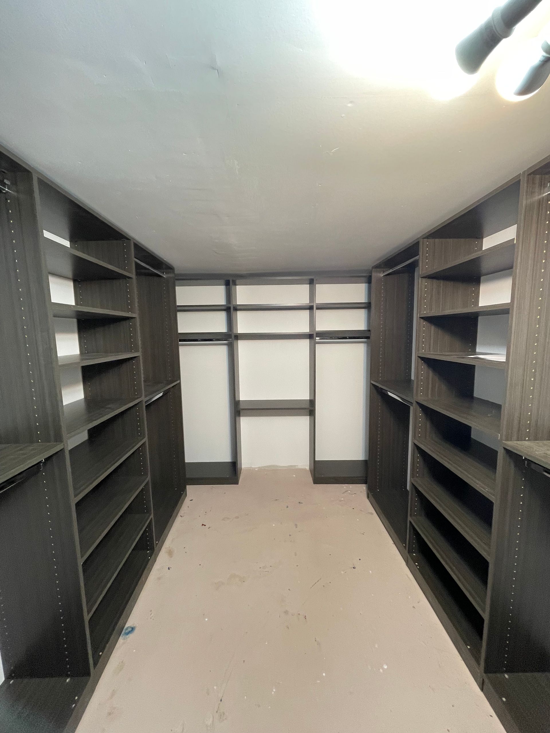 Empty dark wood closet with shelves and hanging rods.