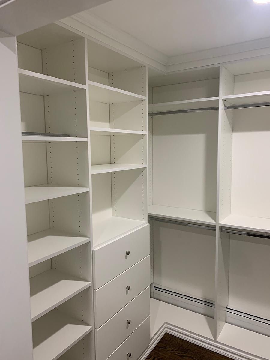 White, built-in closet with shelves, drawers, and hanging rods. The closet is empty.