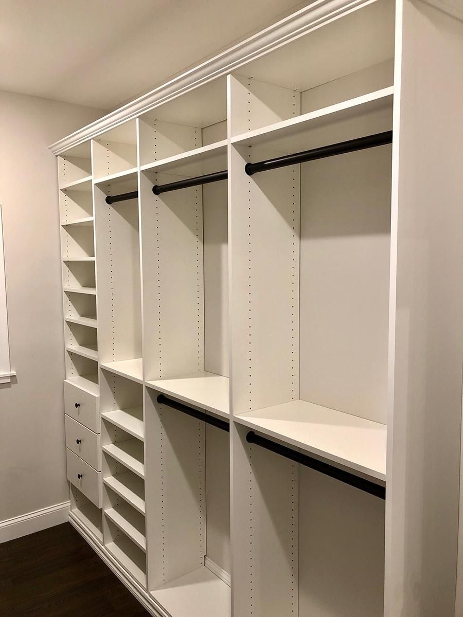 White custom closet with shelves, drawers, and hanging rods.