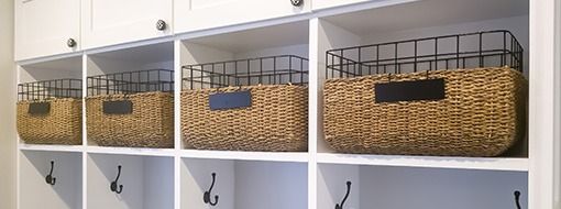 White built-in storage unit with woven baskets and hooks.
