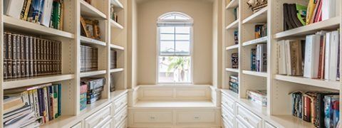 A cozy library nook with built-in bookshelves on either side of a window seat.