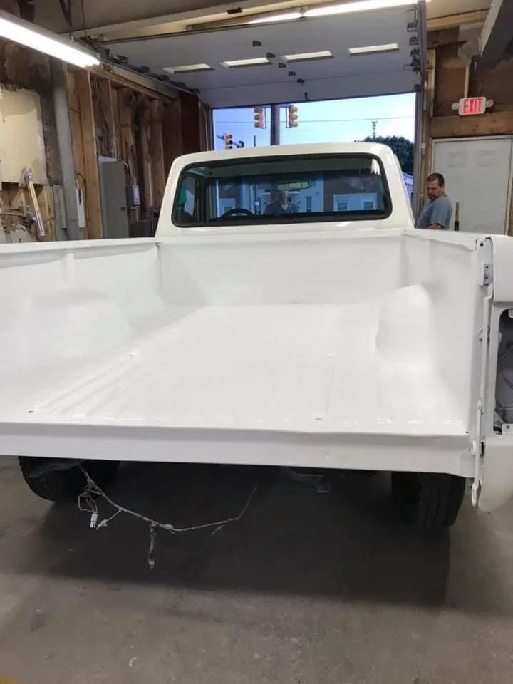 White pickup truck bed in a garage, freshly painted.