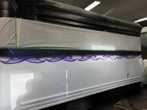 White vehicle with purple wave design, black top, and green tape in a workshop.