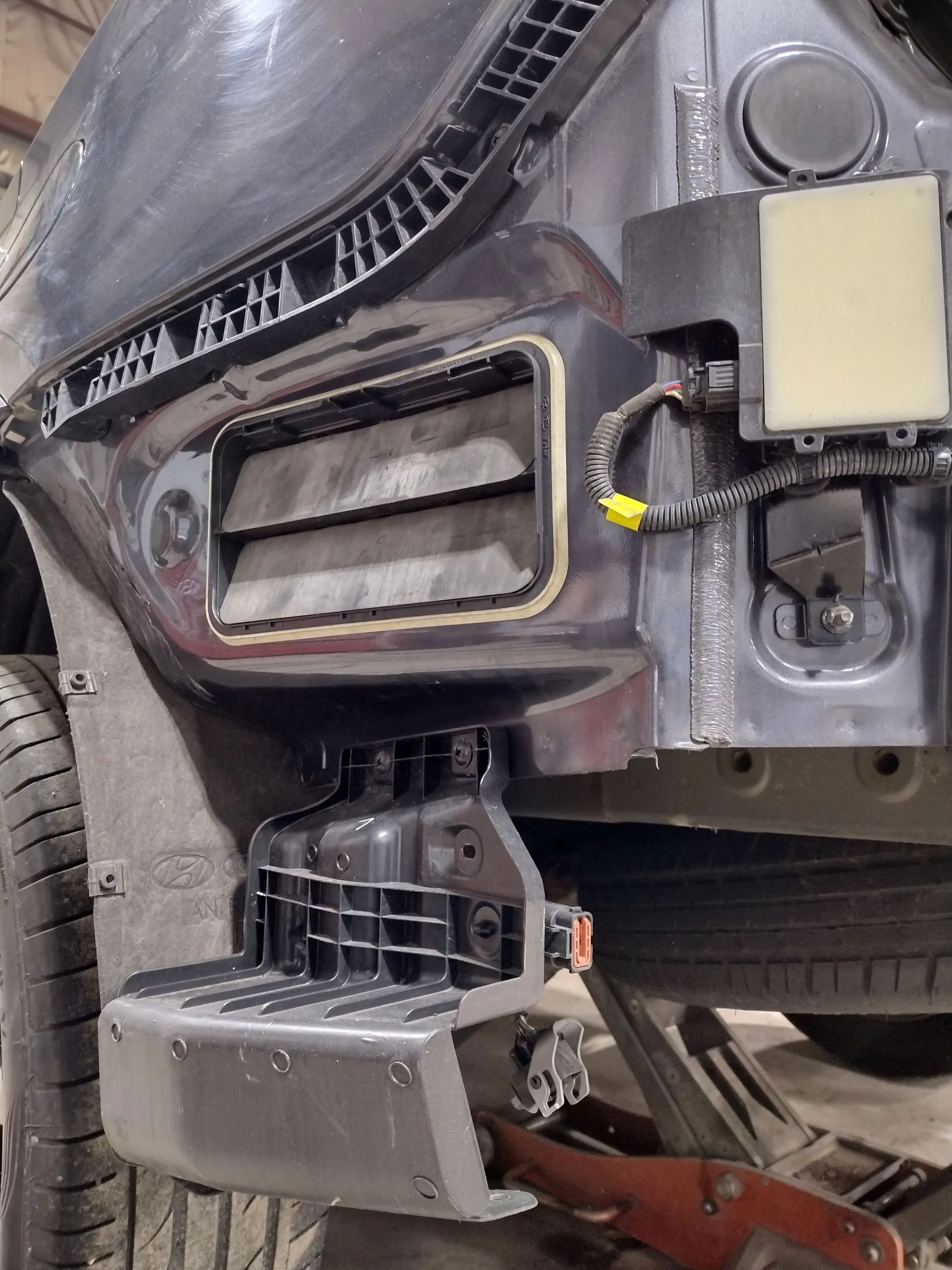 Car bumper's internal components exposed. Shows radiator vents, wiring, and support structures during repair.