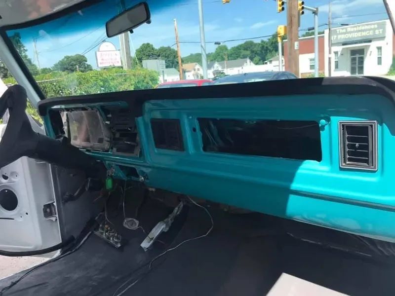 Turquoise classic car dashboard, partially disassembled, with empty gauge cluster.