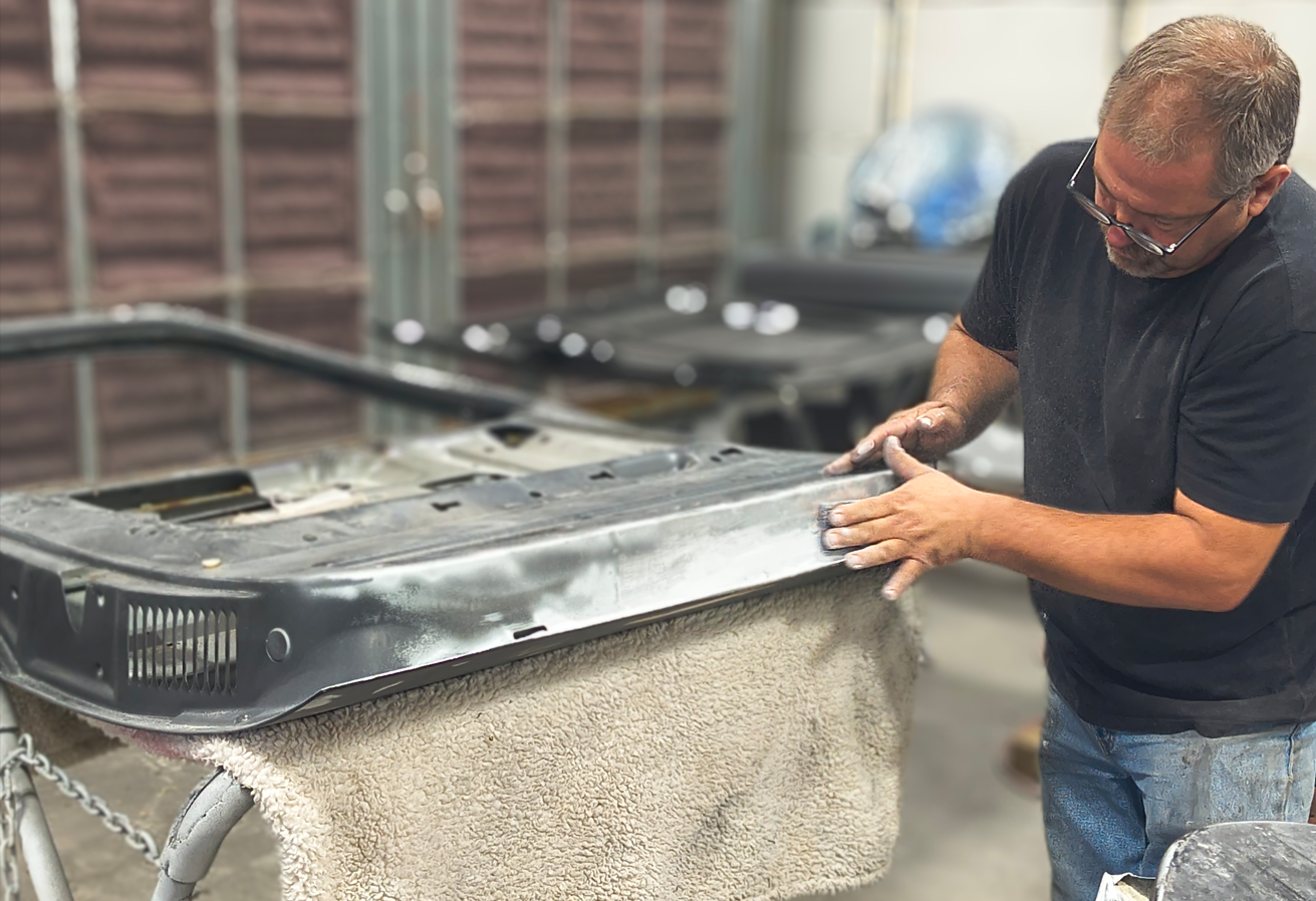 Man sanding a car door in a workshop.
