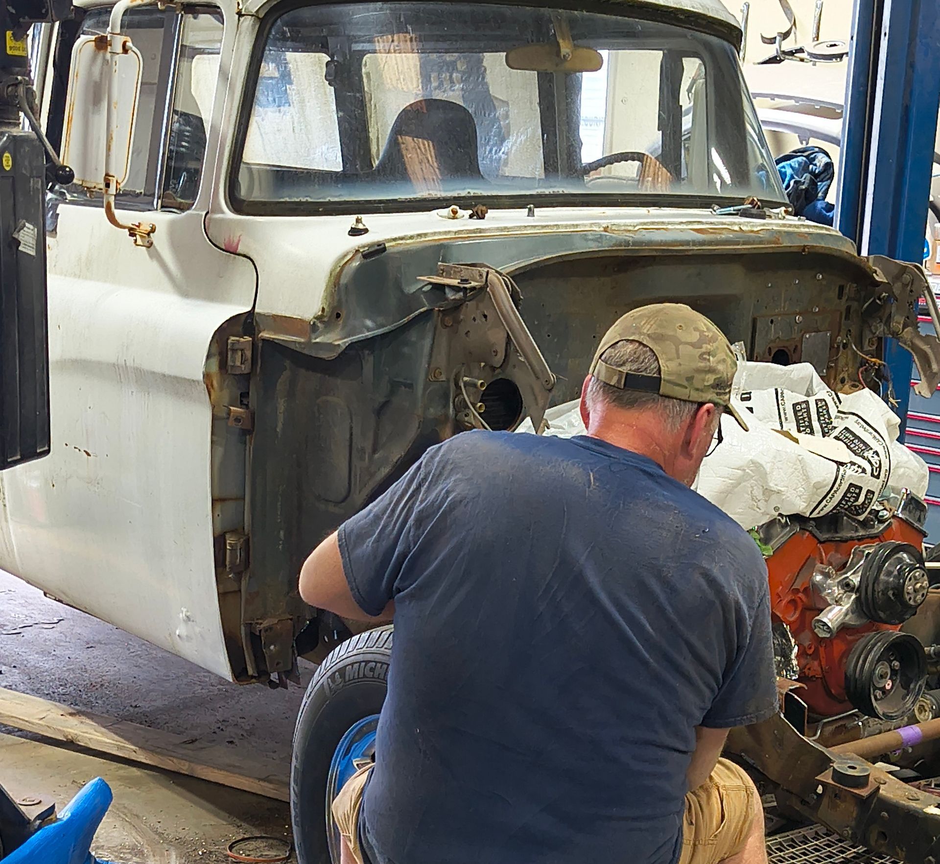 A person working on an old white truck in a garage.