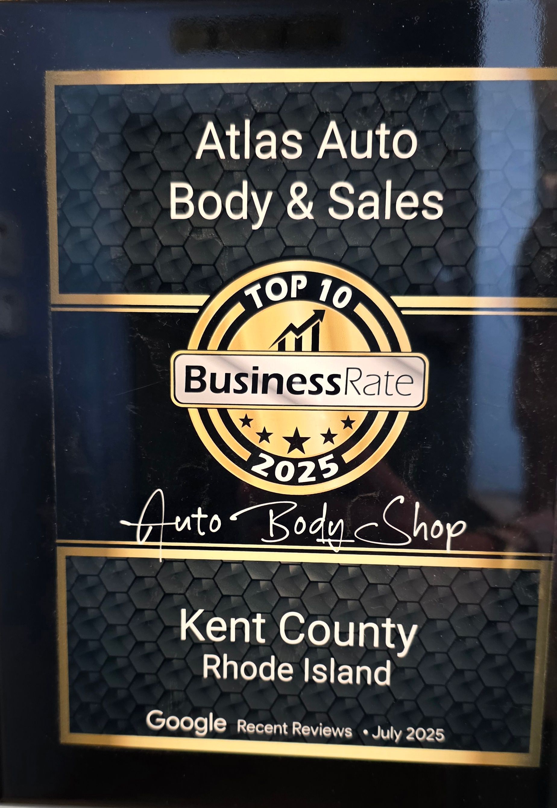 A black and gold award plaque for Atlas Auto Body & Sales, named a top 10 business in Kent County, Rhode Island for 2025.