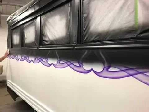 White vehicle side being airbrushed with purple flames, black window frames.