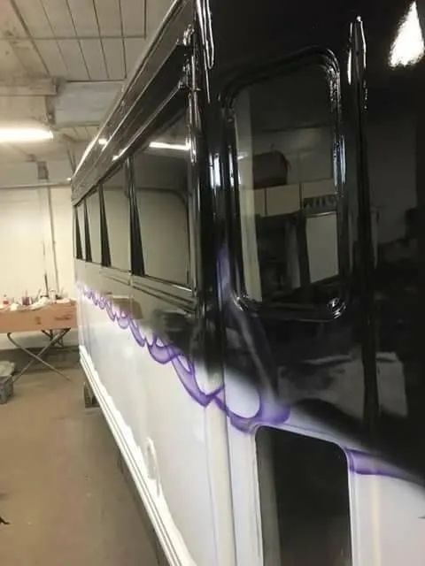 Side view of a white vehicle with black trim and purple flame detailing, indoors.