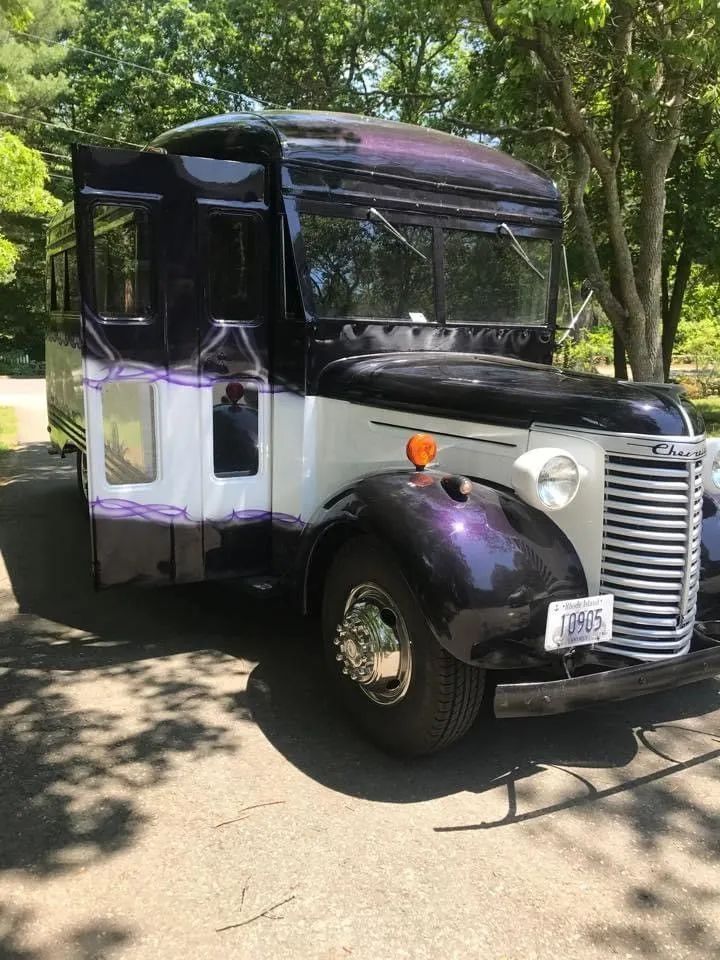 Customized vintage truck, white body, dark purple roof and accents, parked outdoors.