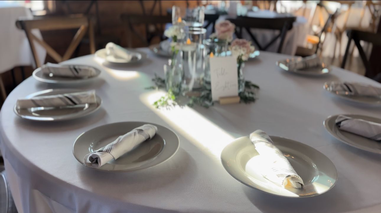 A table set for a wedding reception with plates and napkins on it.