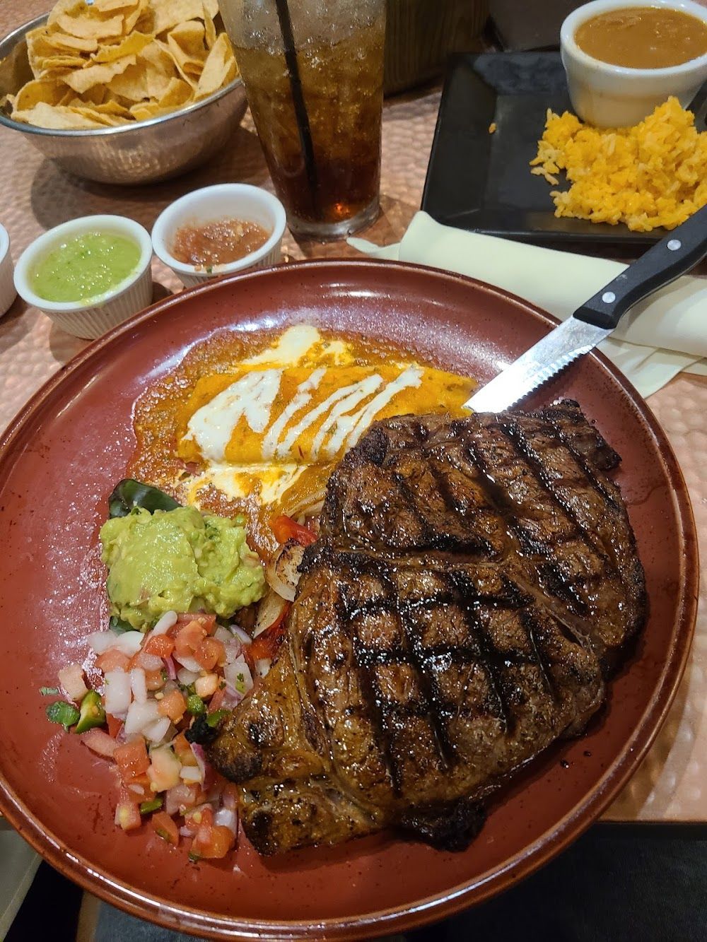 a plate of food with a steak and guacamole on a table