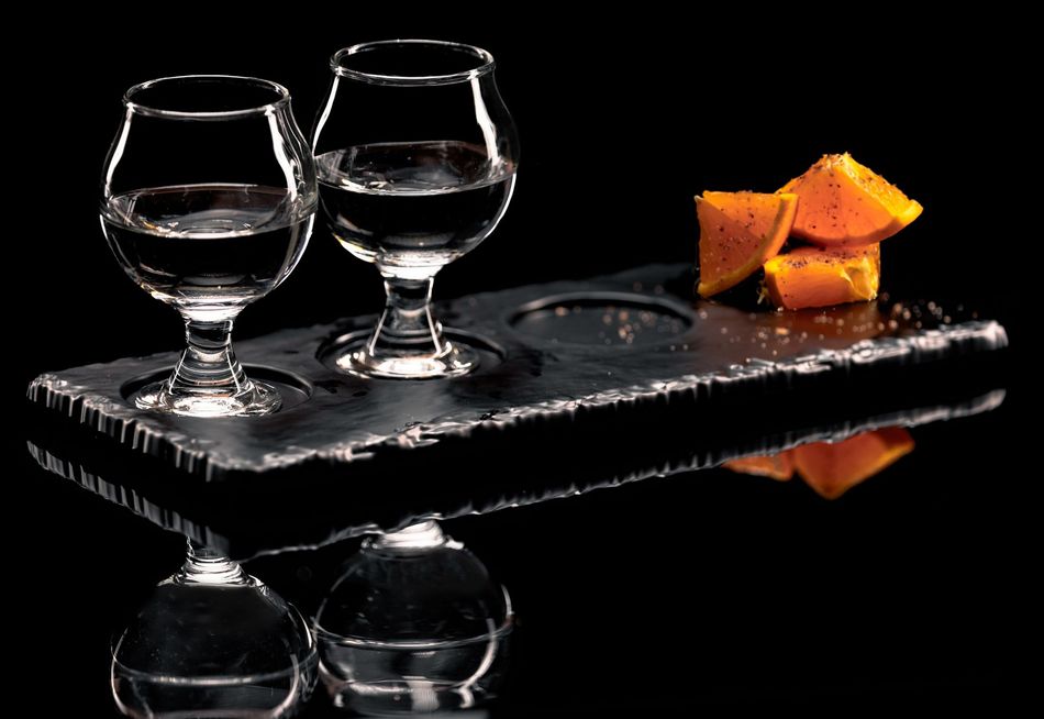 two glasses of water and slices of orange are on a tray .